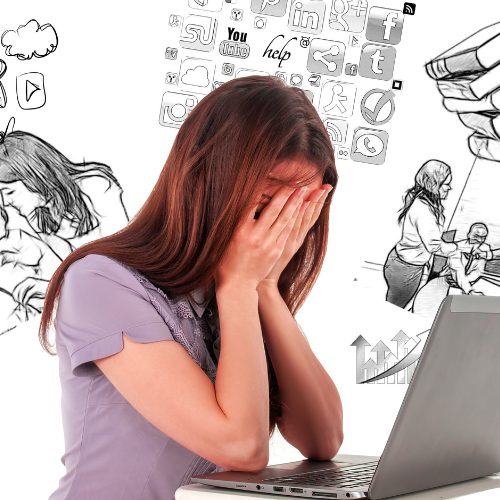 Frau vor einem Laptop, die ihr Gesicht in ihre Hände vergräbt